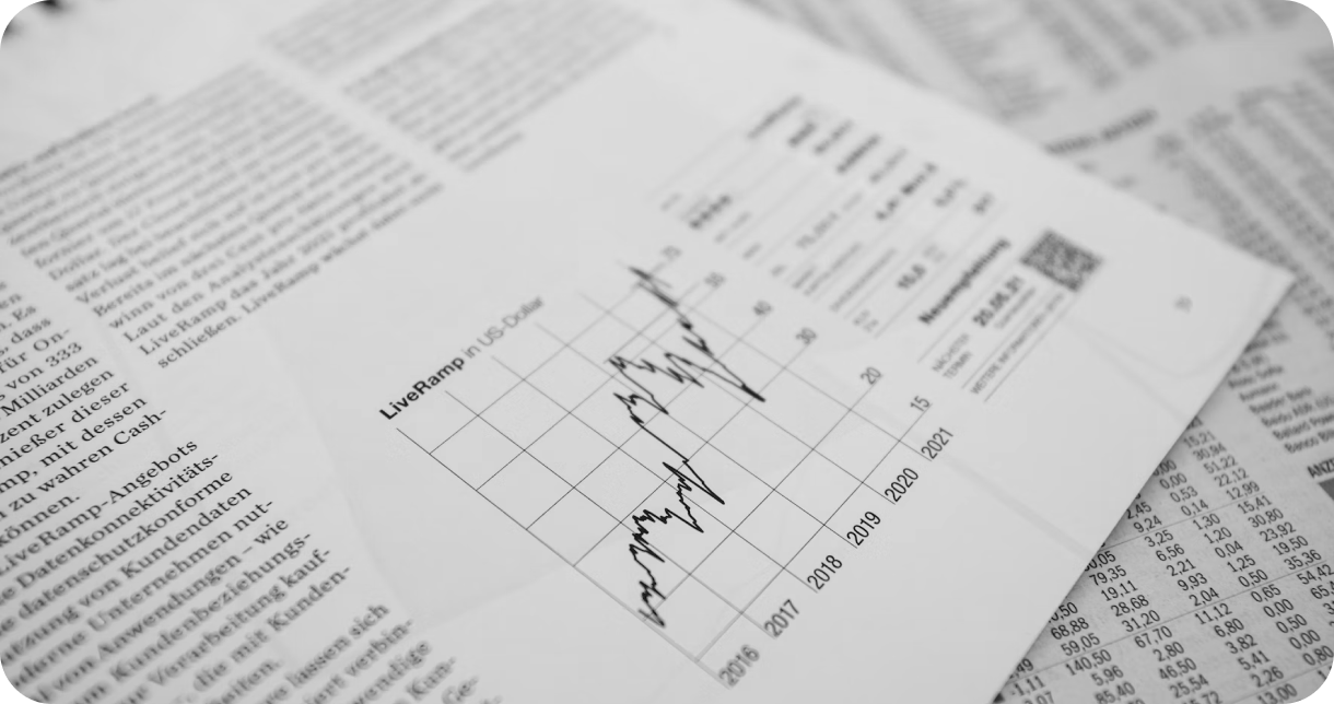 Imagen en blanco y negro de documentos, donde resalta el documento con gráfica de líneas ascedentes